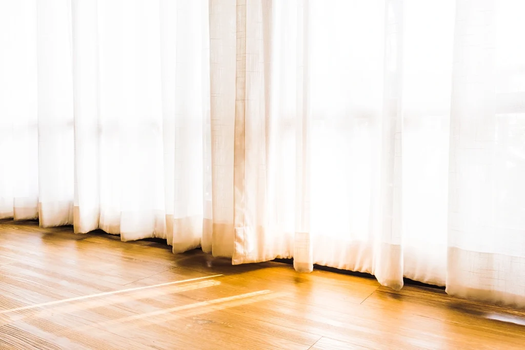 FloorLength Curtains in Modern Living Room REGAL Curtains REGAL Curtains Elegant beige floor-length curtains softly touching the wooden floor in a sunlit modern living room.
