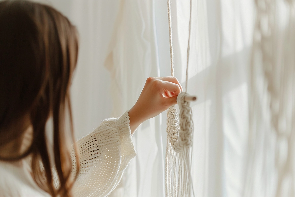 How to Hang Curtains StepbyStep Installation Guide REGAL Curtains Close-up of a person adjusting handmade curtain cords with natural sunlight filtering through sheer drapes.
