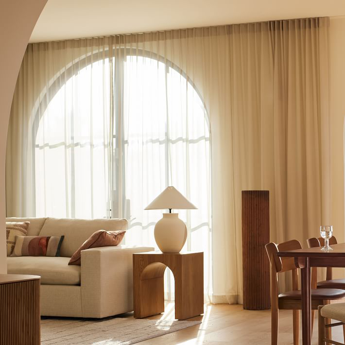 Layered Curtains on Arched Window in Modern Living Room REGAL Curtains REGAL Curtains Modern arched window with layered sheer and blackout curtains in a warm-toned living space.