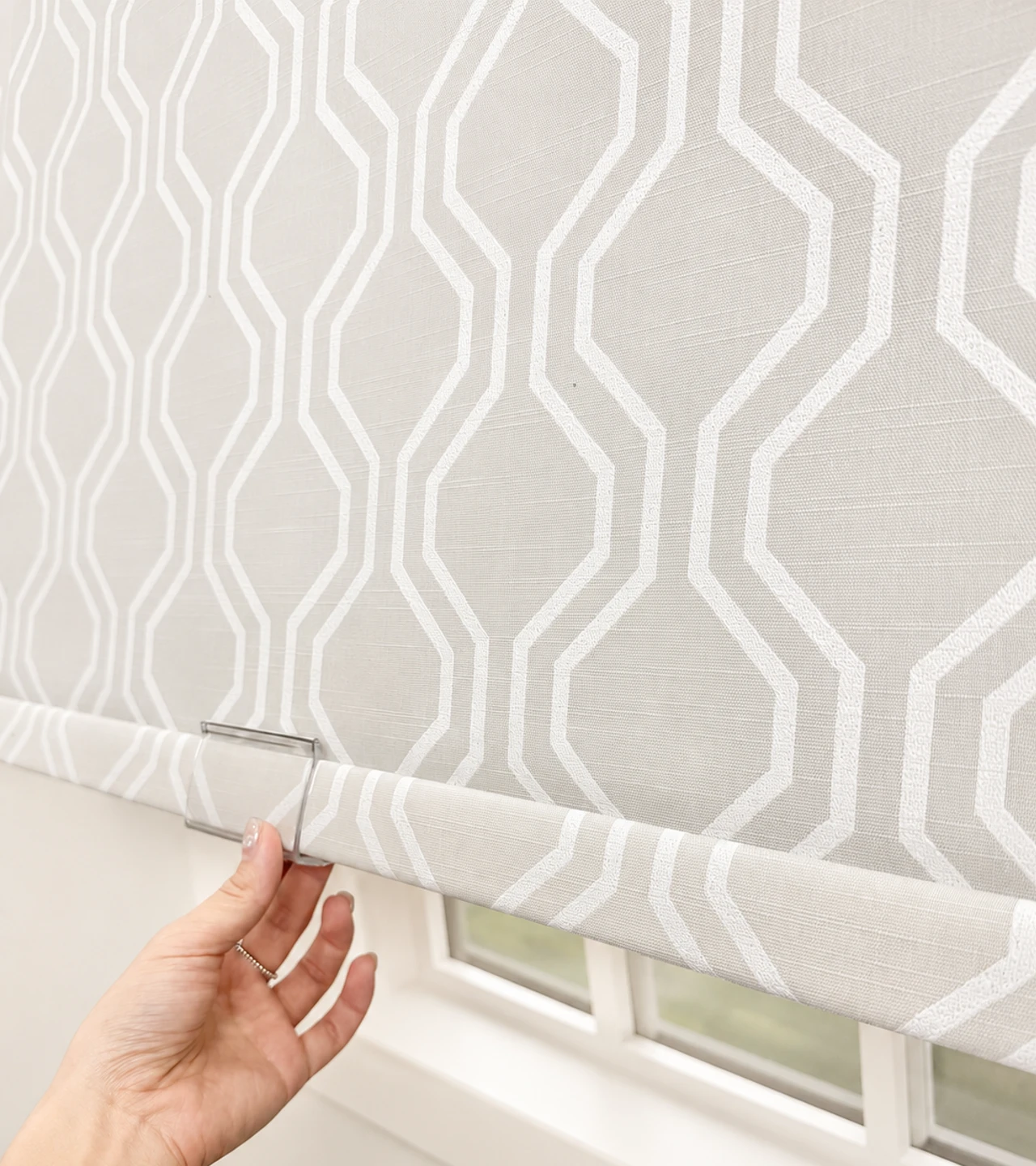 No-drill waterproof roller shades being raised by hand with the integrated bottom rail